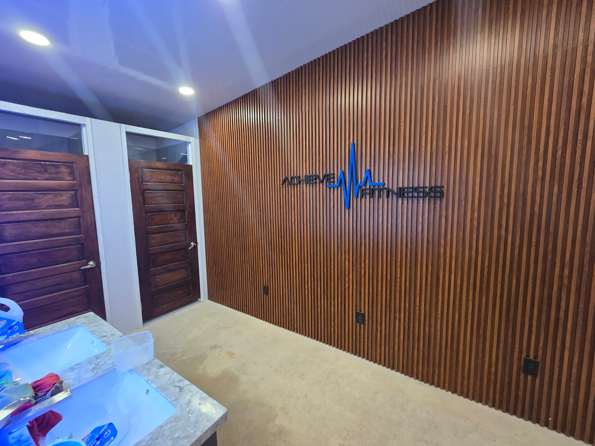 Opening day inside Achieve Fitness, showing the wood wall and sign